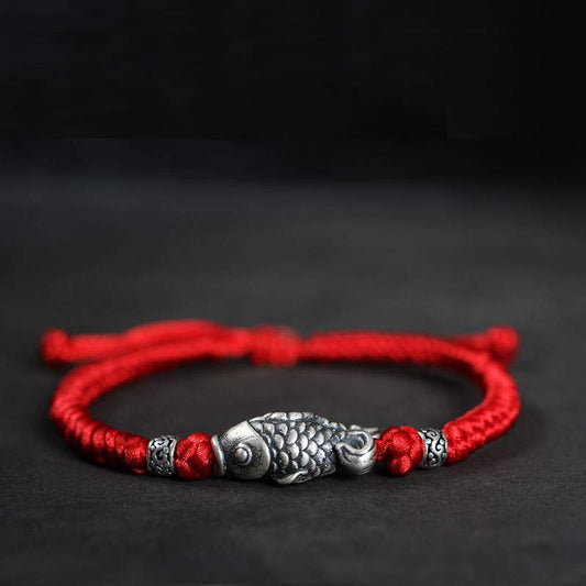 Bracelet ancien tibétain bouddhiste en fil rouge tressé avec des carpes koï en argent, symbole de chance.
