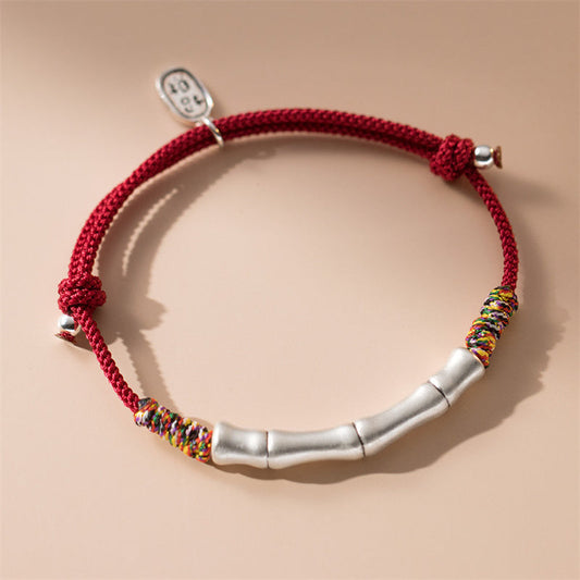 Bracelet en corde rouge colorée, symbole de chance et de prospérité, porté selon la tradition bouddhiste tibétaine ancestrale. Argent sterling 999, bambou et corde rouge.