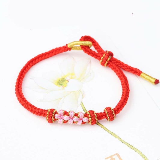 Bracelet tibétain ancien bouddhiste à la corde rouge, fait main, orné de trois fleurs de pêcher, porte-bonheur, à huit brins tressés, selon la tradition du fil rouge.