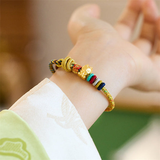 Alte tibetisch-buddhistische Tradition: Geflochtenes Armband mit roter Schnur, Symbol für das Jahr des Drachen, Koi-Karpfen, Mahjong-Würfel, Pfirsichblüten und Kupfermünzen.
