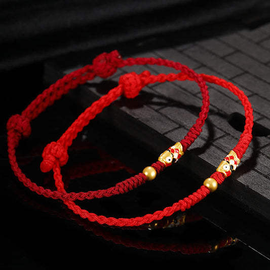 Bracelet tressé artisanal en or 999, symbole de chance, orné d'un poisson koi et inspiré de la tradition bouddhiste tibétaine ancestrale du fil rouge.