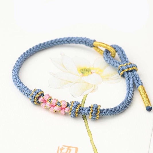 Bracelet tibétain ancien bouddhiste à la corde rouge, fait main, orné de trois fleurs de pêcher, porte-bonheur, à huit brins tressés, selon la tradition du fil rouge.