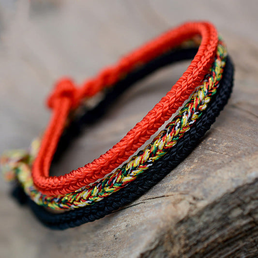 Bracelet tibétain traditionnel à huit fils tressés, orné d'un nœud de paix et de protection, selon la tradition bouddhiste tibétaine ancestrale du fil rouge.