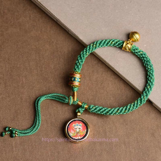 Bracelet tressé en corde rouge, symbole de la tradition bouddhiste tibétaine ancestrale, représentant les cinq dieux de la richesse (Thangka), une roue de prière porte-bonheur et une clochette.
