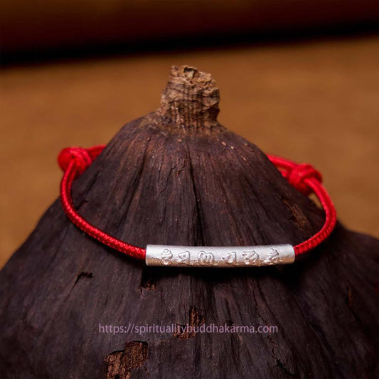 Handgefertigtes Armband aus 999er Sterlingsilber mit Om-Mani-Padme-Hum-Motiv und rotem Seil – ein Symbol für Stärke und tibetischen Knotenschutz.
