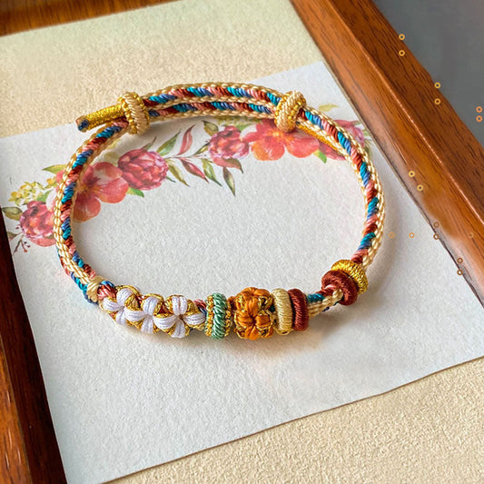 Alte tibetisch-buddhistische Tradition: Handgefertigtes Armband aus rotem Faden in Dunhuang-Farben mit Pfirsichblütenmuster 