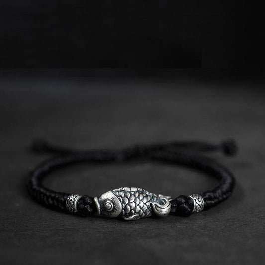 Bracelet ancien tibétain bouddhiste en fil rouge tressé avec des carpes koï en argent, symbole de chance.