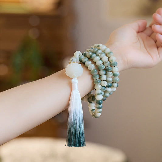 Bracelet Mala naturel de 108 perles, orné de graines de Bodhi, de lotus et d'un pompon gravé, symbole de spiritualité, de bouddhisme et de karma.