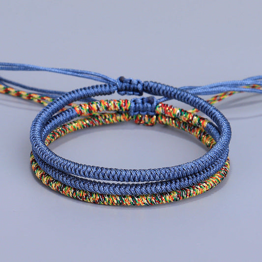 Bracelet porte-bonheur tibétain en corde bleu marine et multicolore, symbole de sagesse spirituelle et d'équilibre énergétique.