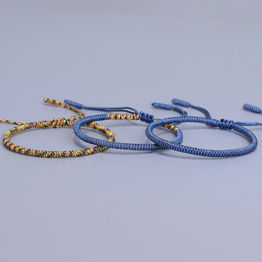 Bracelet porte-bonheur tibétain en corde bleu marine et multicolore, symbole de sagesse spirituelle et d'équilibre énergétique.