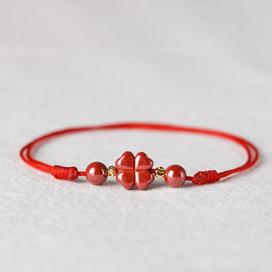 Alte tibetisch-buddhistische Tradition: Armband und Fußkettchen aus rotem Faden mit vierblättrigem Kleeblatt und Zinnobermotiv – ein Segen für Ruhe und Gelassenheit. 