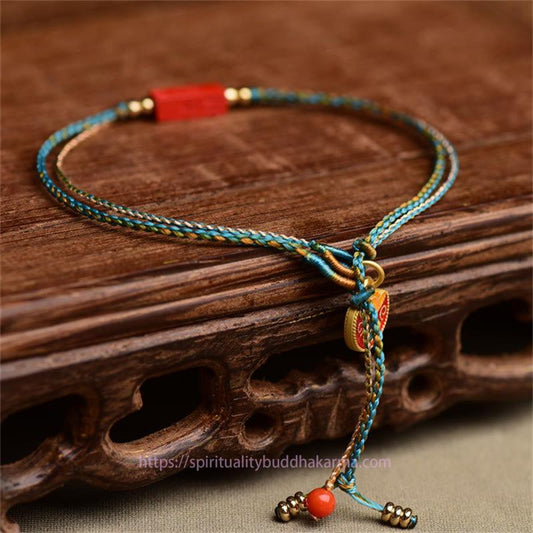 Bracelet double couche tressé à la main en cinabre, selon la tradition bouddhiste tibétaine ancestrale du fil rouge, orné de vœux de bénédiction.