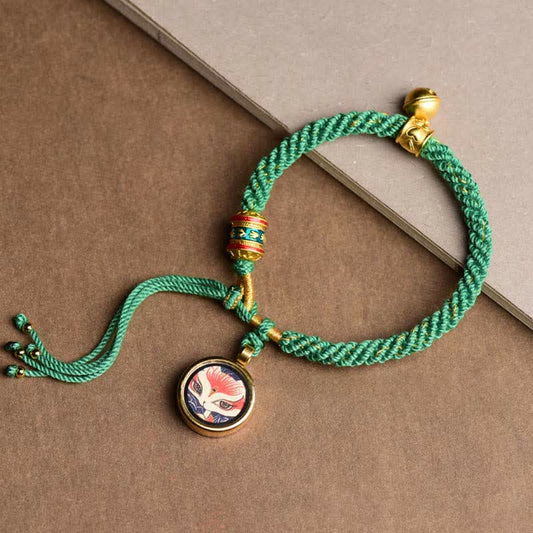 Bracelet tressé en corde rouge, symbole de la tradition bouddhiste tibétaine ancestrale, représentant les cinq dieux de la richesse (Thangka), une roue de prière porte-bonheur et une clochette. 
